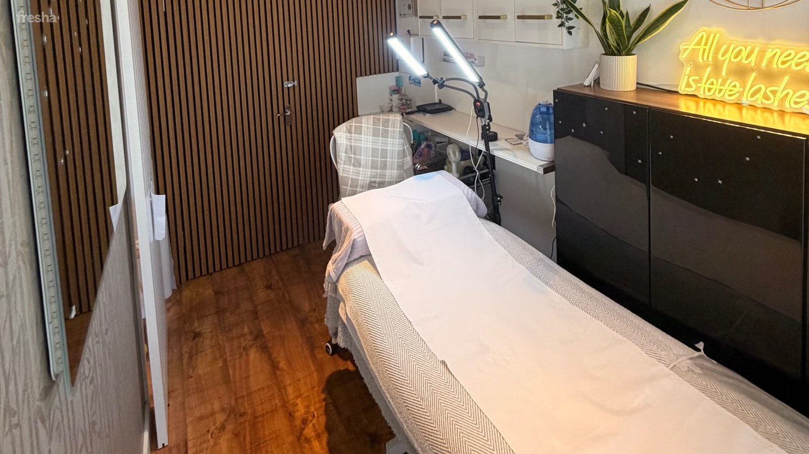 Inside Flirty Studios: the treatment bed, wood panelling and illuminated lash sign.